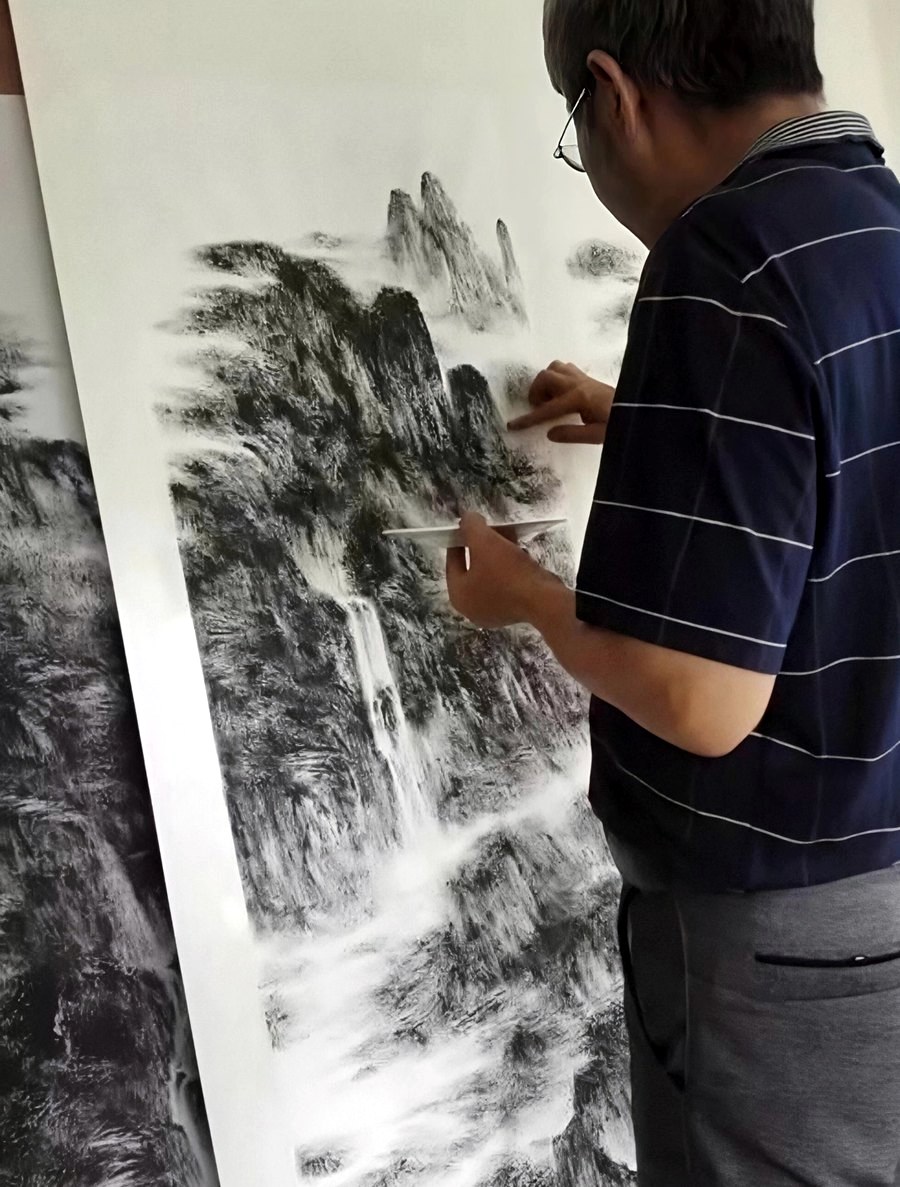 He Zhenquan painting a monumental handscroll with his fingertip, holding the ink plate in his other hand